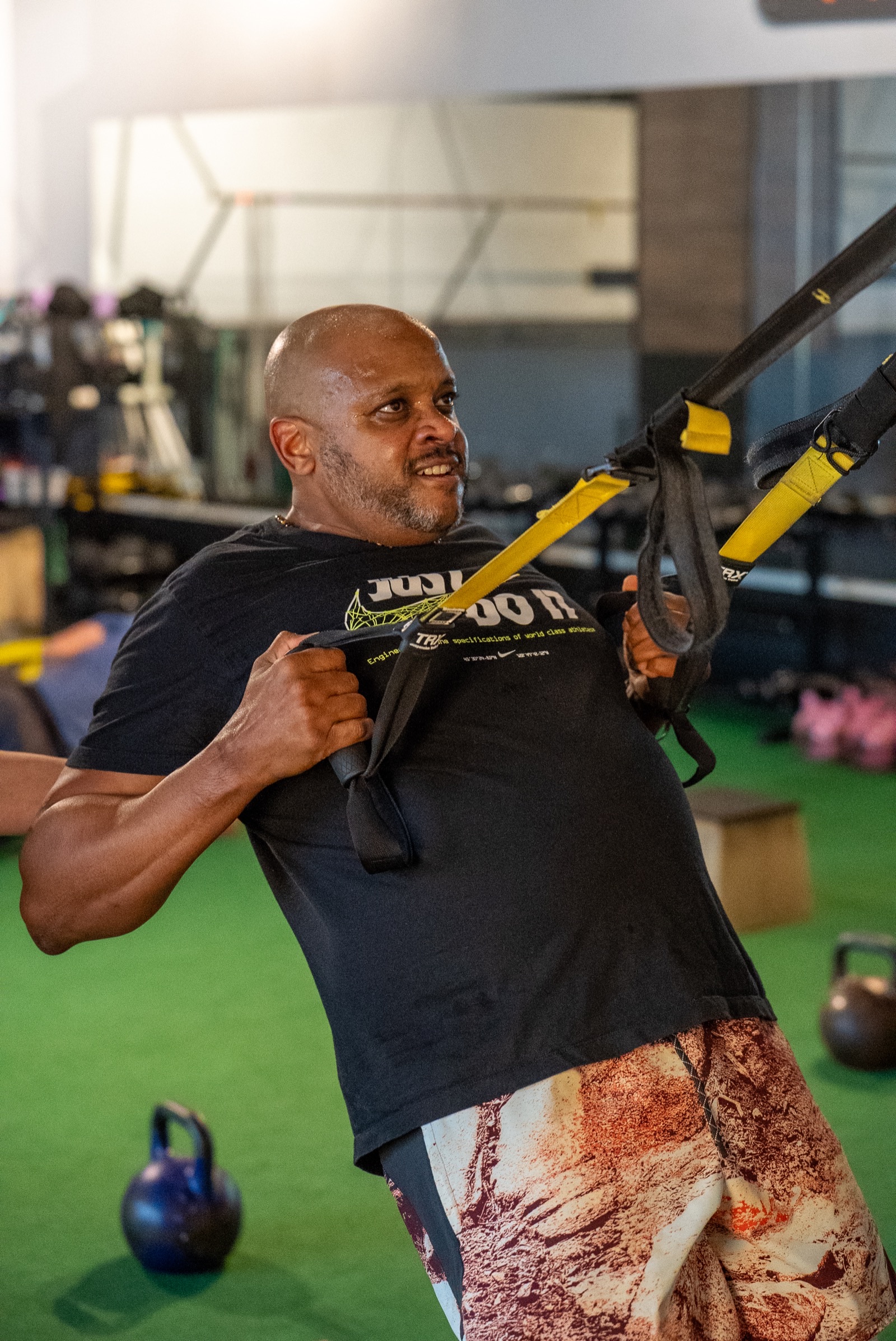 Physics-based movement coaching at Fulcrum Fitness Portland — coach adjusting form during TRX training