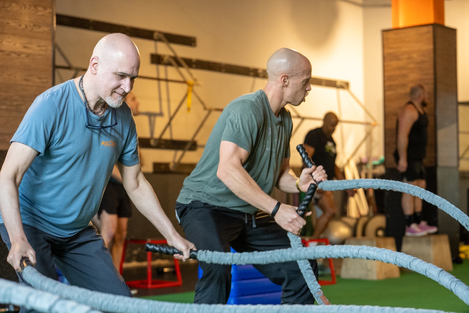 Team training session at Fulcrum Fitness Portland — members doing battle ropes in group workout class